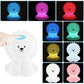 Veilleuse lion LED multicolore sur une table en bois